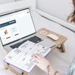 a person sitting on a bed with a laptop