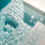 a pool with clear blue water and a white bench