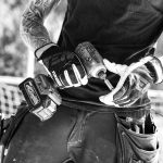 a black and white photo of a man holding a pair of gloves